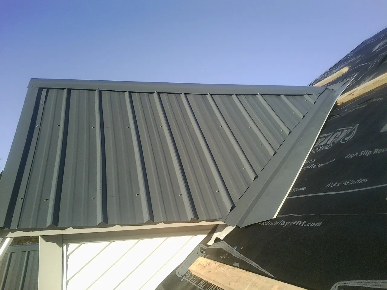 Gray metal roof panels going on over a garage gable in Urbana
