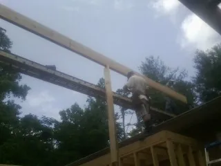 Carpenter setting a ridge beam over a new addition frame — Ice Dam Removal by Roofing Brothers in Urbana
