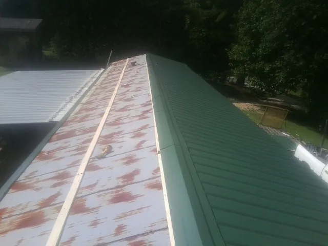 Old rusted panels beside newly installed green metal roofing — Wind Damage Roof Repair by Roofing Brothers in Urbana